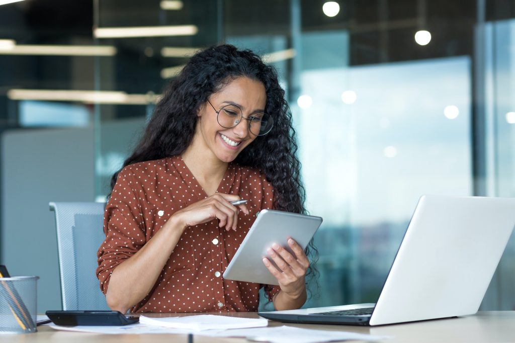 Young beautiful Latin American woman working inside modern office building, paperwork woman uses