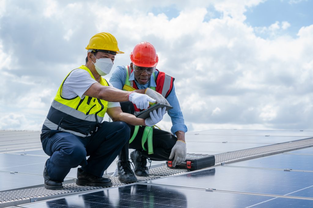 Technician checking solar panels on factory roof, Environment friendly.