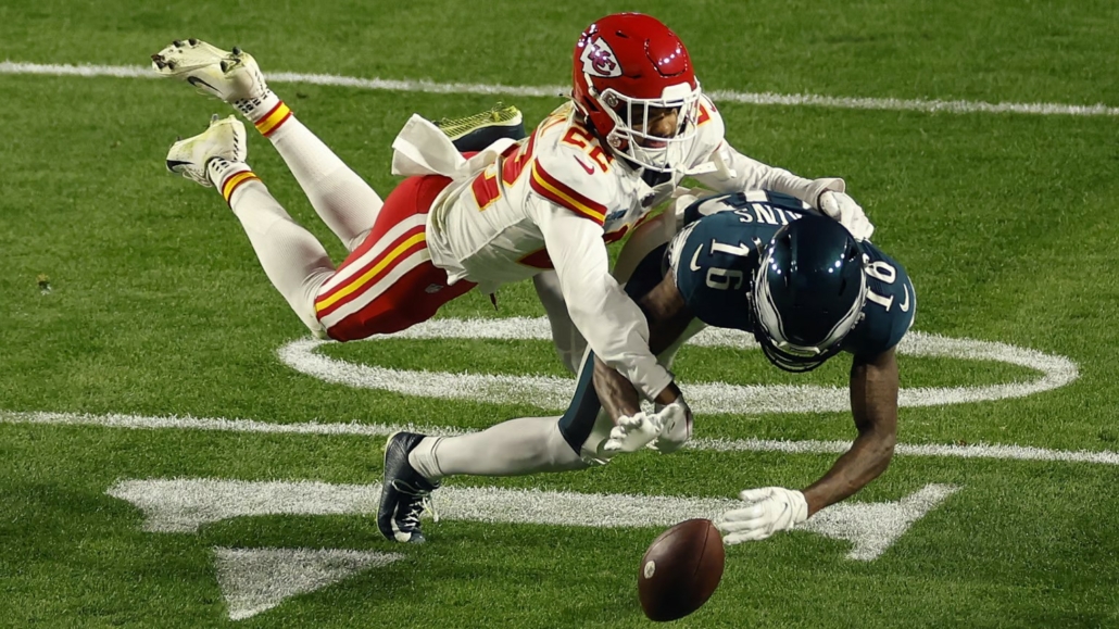 The image shows a photograph of a tackle between two players in the National Football League in the United States.