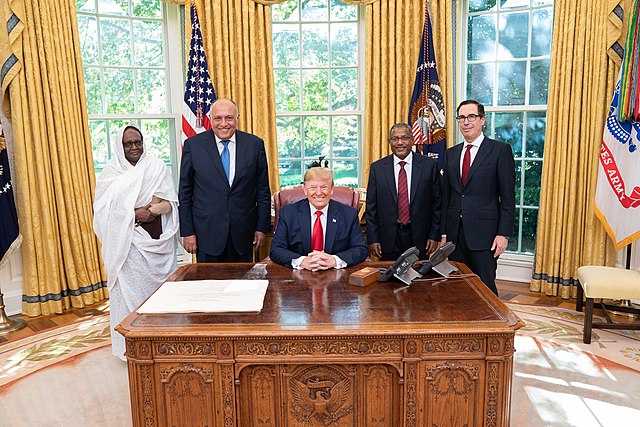  Adult, Male, Man, Person, Accessories, Formal Wear, Tie, Indoors, People, Glasses, Crowd, Appliance, Blow Dryer, Device, Electrical Device, Flag, Steven Mnuchin, Sameh Shoukry, Donald Trump, Draupadi Murmu
