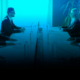 Why is Shadow AI dangerous for diplomats? 3 People, Person, Audience, Crowd, Indoors, Lecture, Room, Seminar, Adult, Female, Woman, Male, Man, Clothing, Coat, Accessories, Formal Wear, Tie, Jacket, Blazer, Face, Head, Conversation