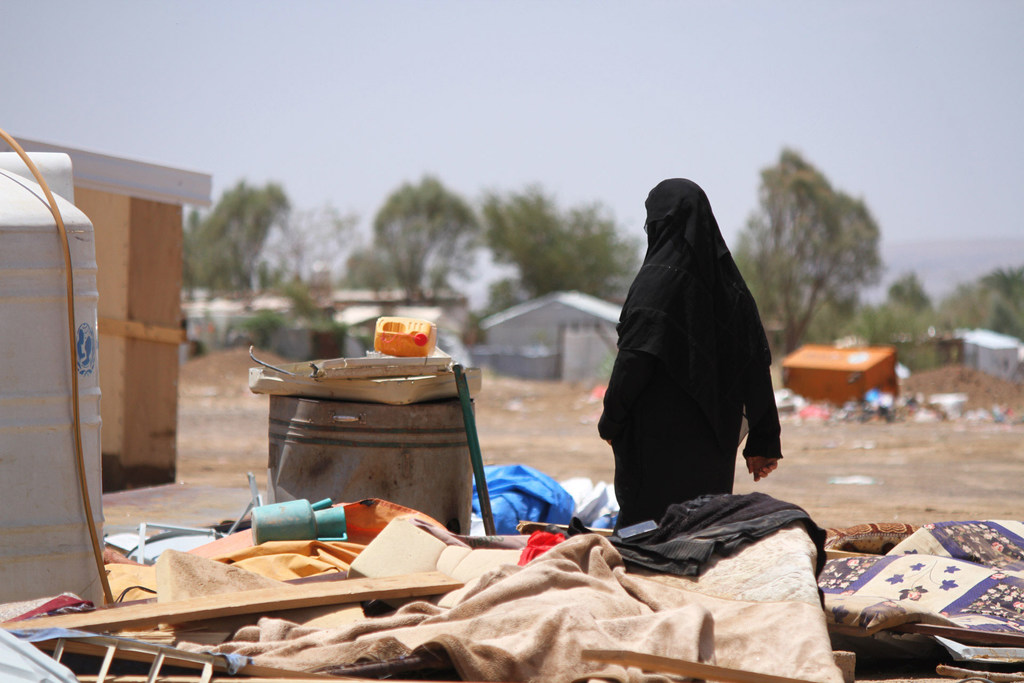 Wars that outlast attention: The role of humanitarian diplomacy 2 The image shows a photograph of a woman walking past piled belongings