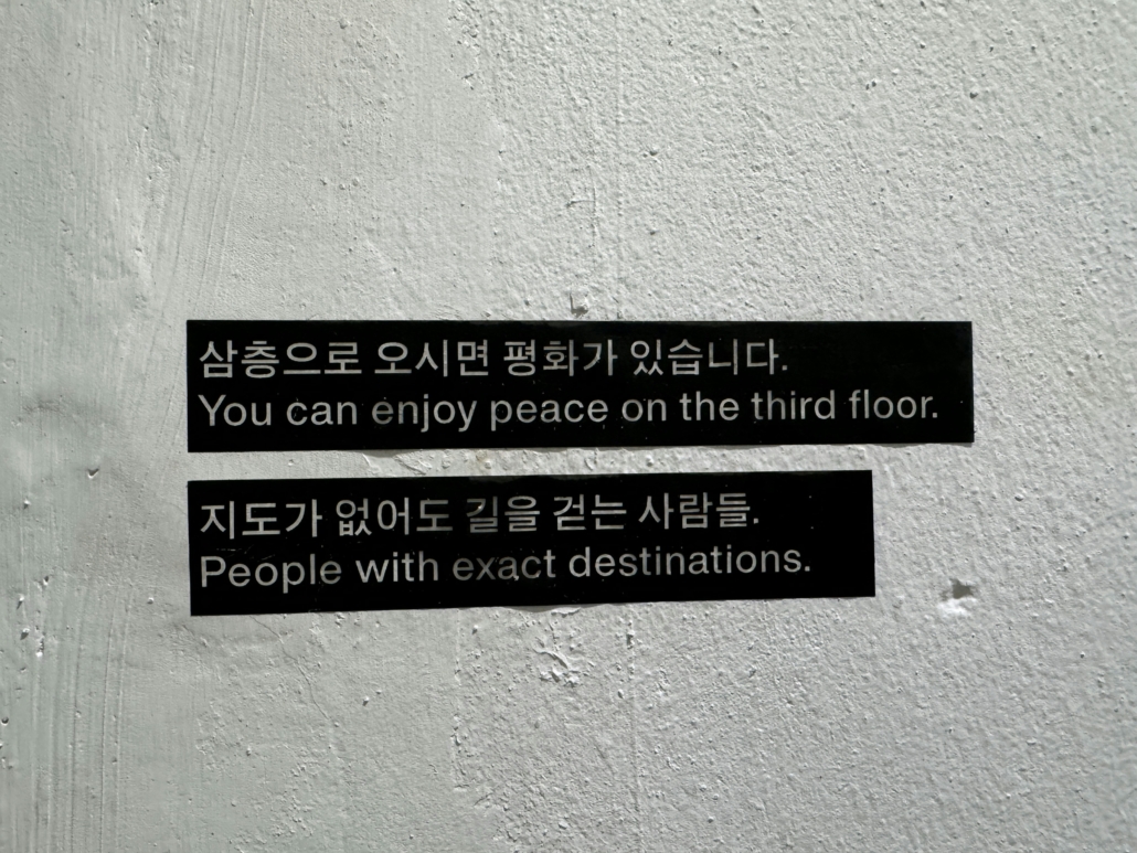 The image shows a wall with two signs. One says: You can enjoy peace on the third floor. The second says: People with exact destinations.