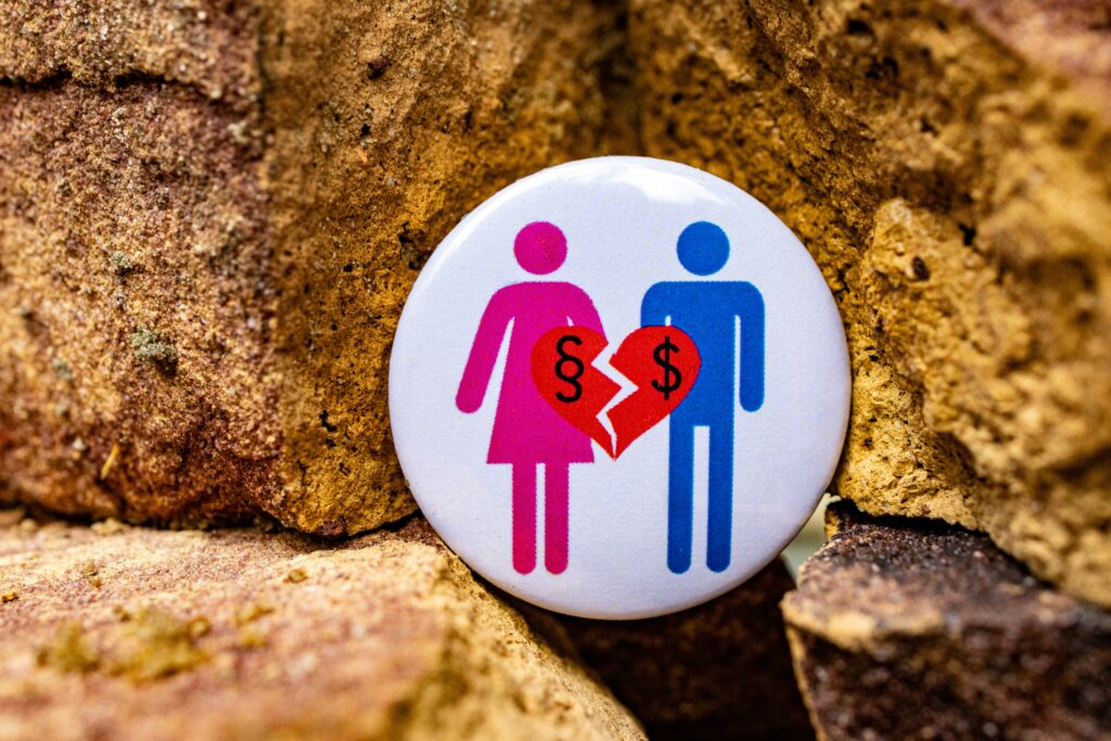The image shows a button badge with a man and woman figure and a broken heart